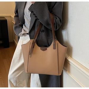 Close-up of the pebbled leather texture and logo detail on a brown tote bag
