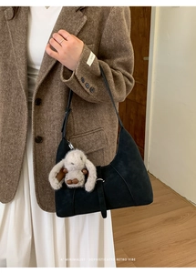 Detail der schwarzen Hobo-Tasche aus Wildleder mit Plüschhasen-Anhänger und Schultergurt