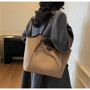 Detail of beige lychee grain leather tote bag with brown shoulder strap on model