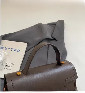 Gros plan d'un sac à main en cuir marron foncé avec poignée rigide et boucles métalliques