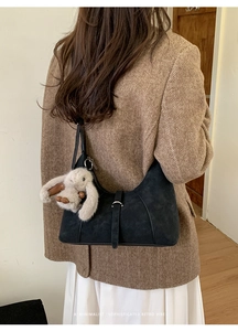 Black matte crescent bag with adjustable buckle strap and a plush rabbit charm