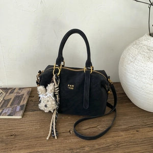 Détail du sac Boston noir avec logo doré PAN 'TOR et charme lapin blanc en peluche