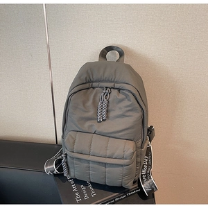 Detailed view of quilted olive backpack featuring lettered straps and textured fabric