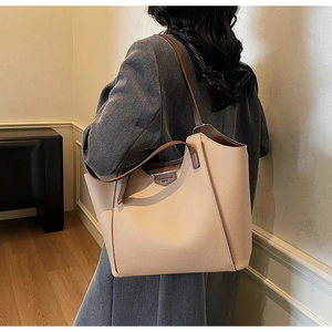 Detail of high-capacity tote bag in beige lychee leather with brown shoulder straps