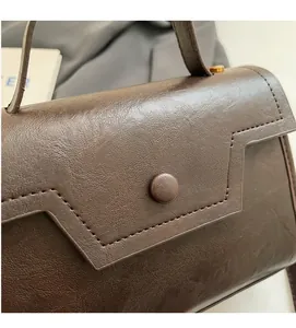 Détail du sac à main en cuir marron foncé avec texture lychee et coutures de précision