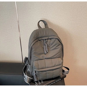 Detail of grey-green quilted backpack with woven rope zipper pulls and wide branded straps