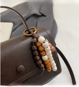 Détail d'un bijou de sac en perles multicolores avec anneau en bronze sur sac en cuir