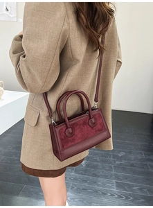 Detail view of burgundy leather handbag styled with a beige blazer for a retro look