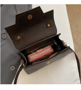 Vue détaillée du sac bandoulière en cuir marron foncé montrant l'intérieur spacieux et le fermoir