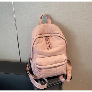 Detail of light pink quilted backpack featuring durable nylon fabric and woven zipper puller