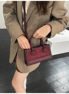 Detail of burgundy frosted suede handbag with contrasting smooth leather handles