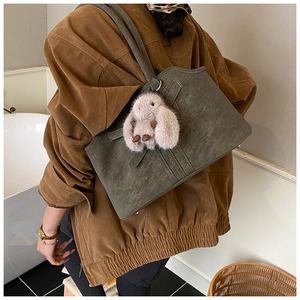 Détail du sac cabas vert olive foncé avec texture cuir mat et un pendentif lapin mignon