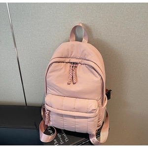 Detailed view of pink quilted nylon backpack featuring durable woven straps and rope zippers