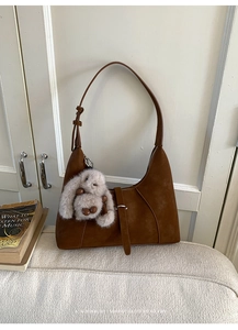 Detailaufnahme der braunen Wildledertasche mit verstellbarem Gurt und Plüschhasen-Anhänger