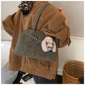 Olive green matte leather tote bag detail with plush rabbit charm and top stitching