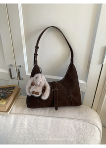 Detail of dark brown suede shoulder bag featuring a cute plush bunny charm and retro design