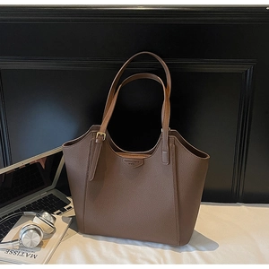 Detail of dark brown pebble leather tote bag with metal buckle and gold logo branding
