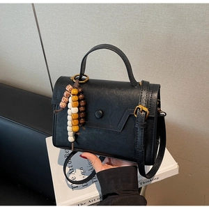 Détail du sac en similicuir noir avec coutures étagées et perles en bois colorées