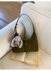 Detail of dark olive green matte handbag with metal buckle and plush bunny charm