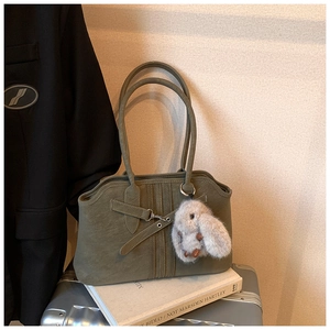 Close-up of olive green vintage tote bag with rabbit charm and stitched design