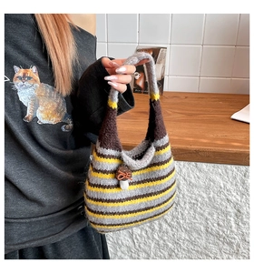Close-up of hand-knitted striped tote bag with a cute red mushroom hanging charm