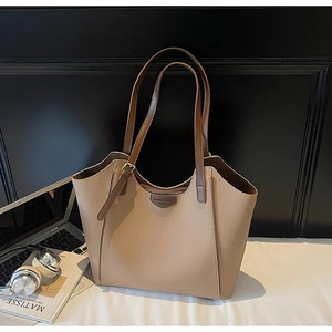 Detail of apricot pebbled leather tote bag with dark brown straps and brand plaque