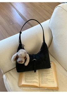 Detail of black matte handbag with a cute plush rabbit charm on a minimalist background