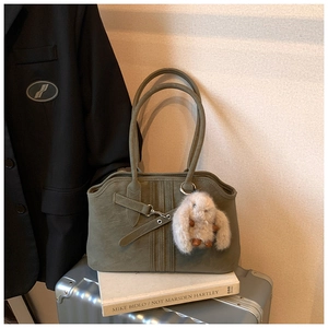 Detail of olive green suede tote bag with cross straps and plush bunny pendant charm
