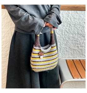 Close-up of knit stripe tote bag with yellow and grey patterns and mushroom charm