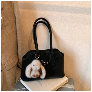 Detail of vintage black tote bag with decorative buckle and white bunny plush charm