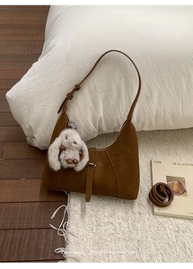 Brown frosted suede crescent bag featuring a plush rabbit charm and dual strap details