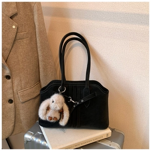Detail of black matte tote bag with vertical stripes and a plush rabbit charm
