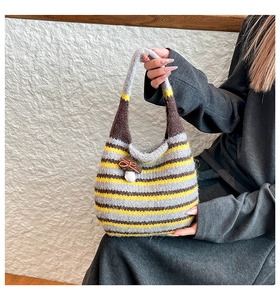 Detail of hand-knitted striped tote bag with mushroom charm and thick yarn texture