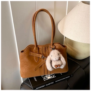 Detail of vintage caramel brown tote bag with suede texture and plush bunny charm
