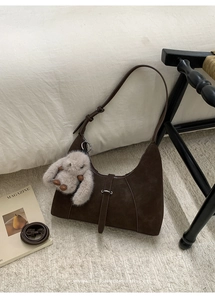 Detail der dunkelbraunen Wildleder-Hobo-Tasche mit Ziernähten und Hasen-Anhänger