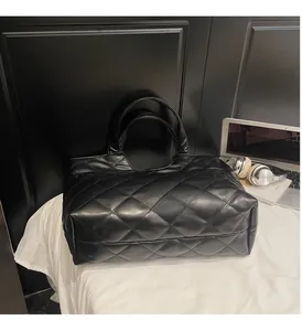 Détail du sac cabas noir matelassé avec surpiqûres en losange et accessoires