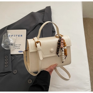 Détail du sac à main en cuir PU crème avec breloque en perles de bois et bandoulière