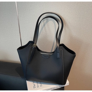Close-up of black pebbled leather tote bag with metallic zipper and shoulder strap detail
