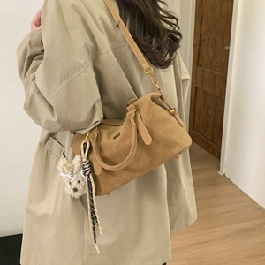 Détail du sac Boston en daim fauve avec breloque lapin en peluche et bandoulière sur mannequin