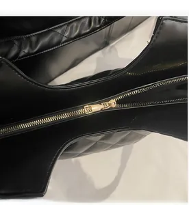 Gros plan sur la fermeture éclair en métal doré et le cuir matelassé noir du sac