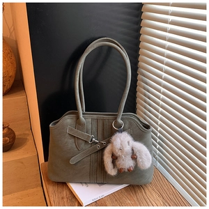 Detail of olive green tote bag with leather strap buckle and cute plush bunny charm