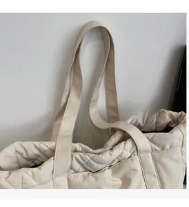Close-up of quilted nylon tote bag showing white diamond stitching and wide strap detail