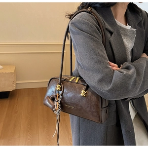 Detalle de bolso Boston vintage en cuero marrón oscuro con herrajes dorados y dije de corazón