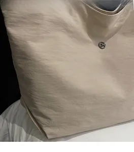 Macro shot of beige nylon tote bag material with a round metallic CM logo buckle