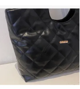 Gros plan sur la texture en cuir matelassé noir et le logo doré d'un sac cabas chic