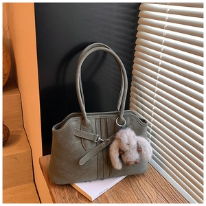 Detail of vintage green leather tote bag featuring silver buckle and plush rabbit charm