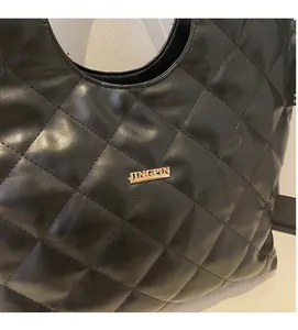 Détail du sac à bandoulière en similicuir noir matelassé avec logo doré et losanges