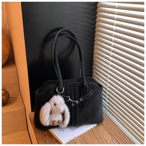Detailed view of black suede tote bag with metal eyelets and cute rabbit pendant