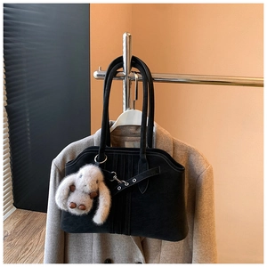 Macro detail of black matte shoulder bag with metallic eyelets and rabbit plush charm