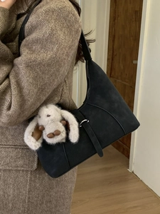 Schicke schwarze Hobo-Bag aus mattem Wildleder mit weißem Plüschhasen-Anhänger am Mantel